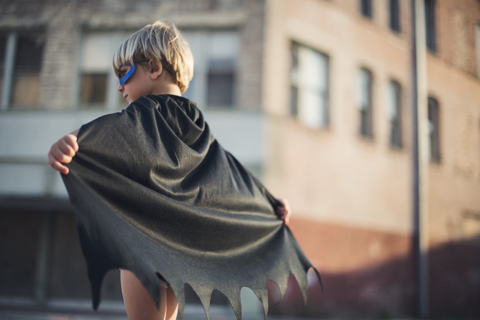 Child in superhero costume with cape and mask