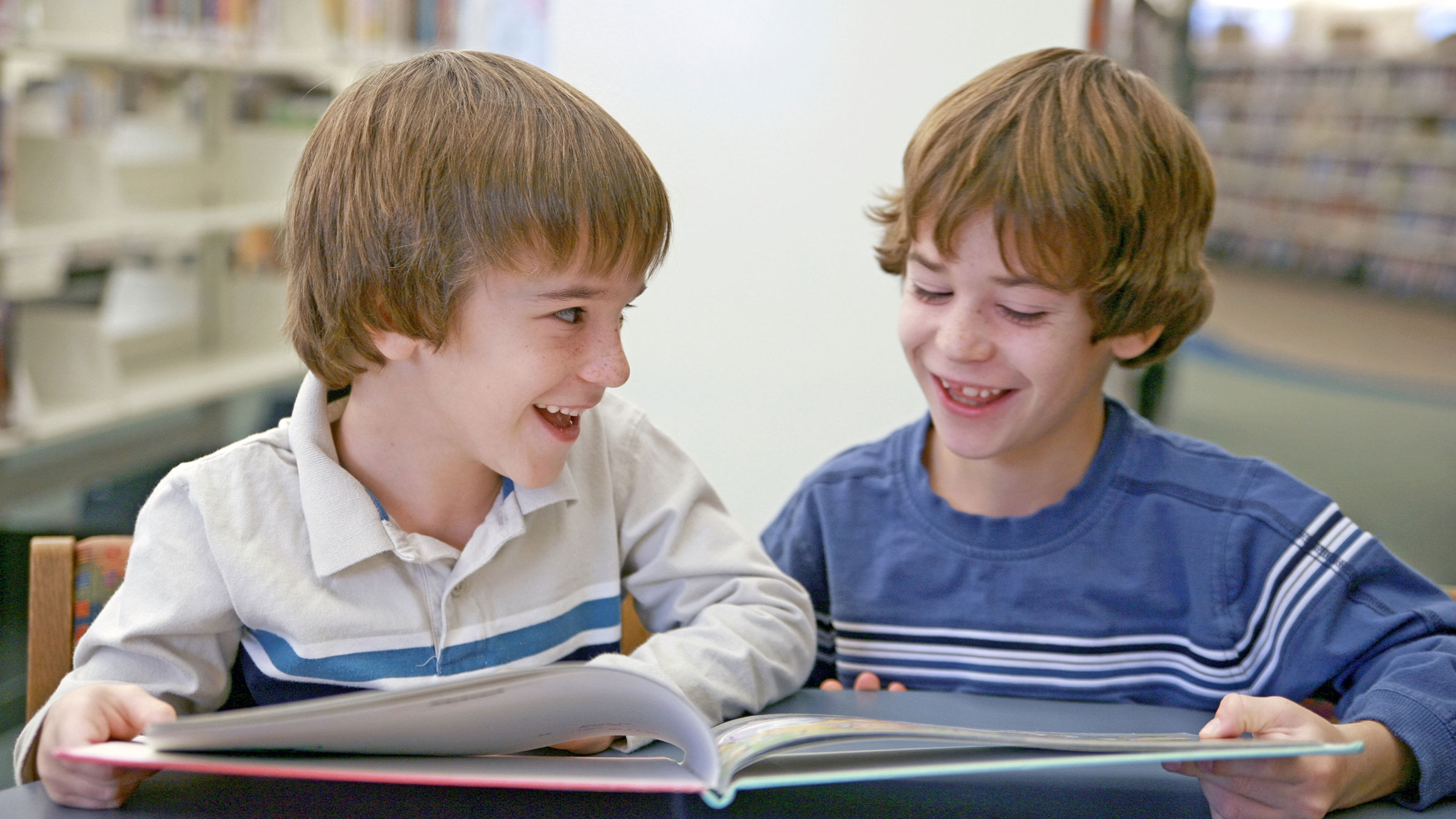 Two middle school children reading a book in a library