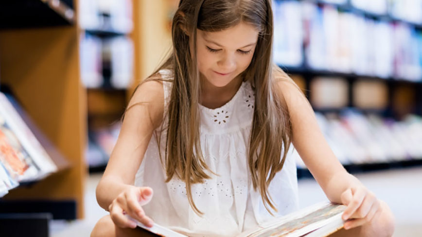 Middle school girl reading in a library