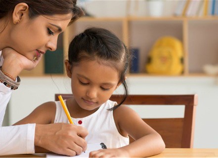 Girl working on handwriting with her mother at a table