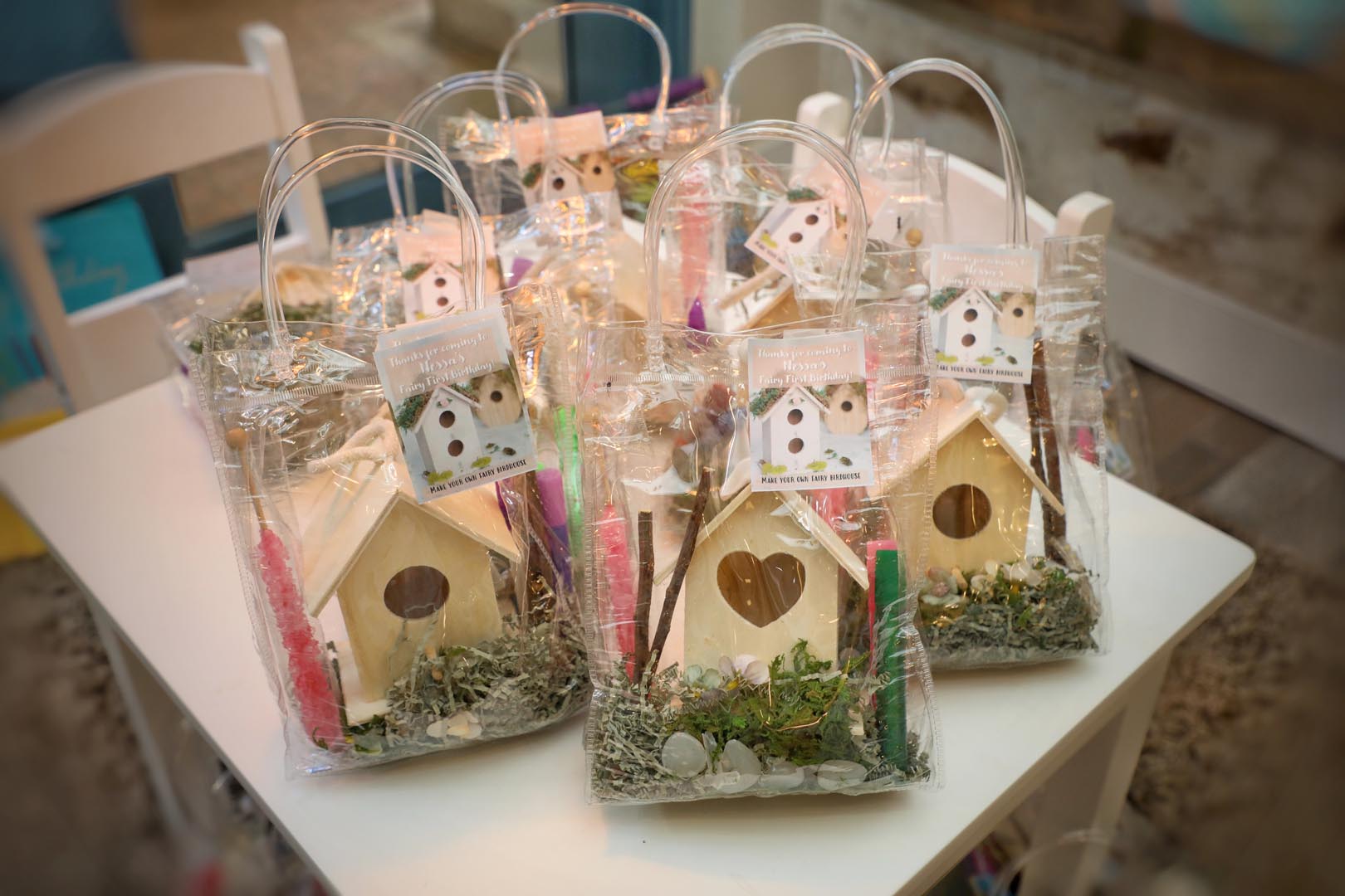 Decorative birthday party celebration gift bags shaped like bird houses surrounded by grass