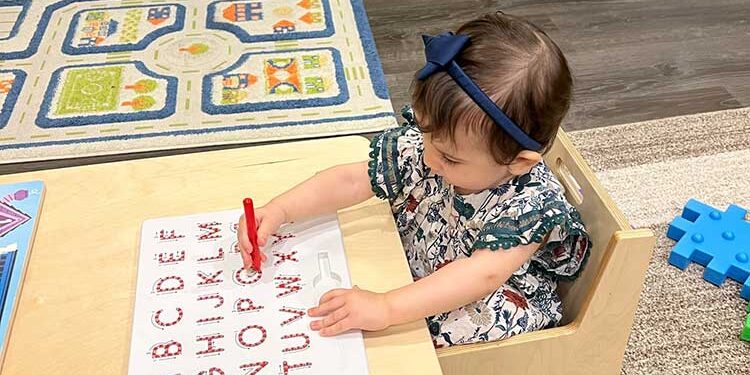 Small toddler sitting at a desk writing the alphabet