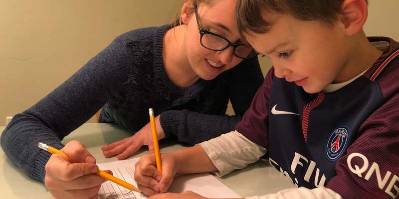 Student learning to write the alphabet with his teacher