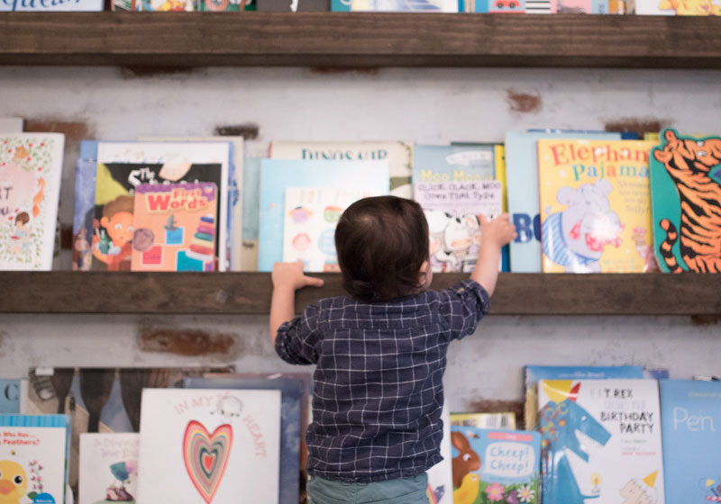 Child selecting a book from a wall of children's books